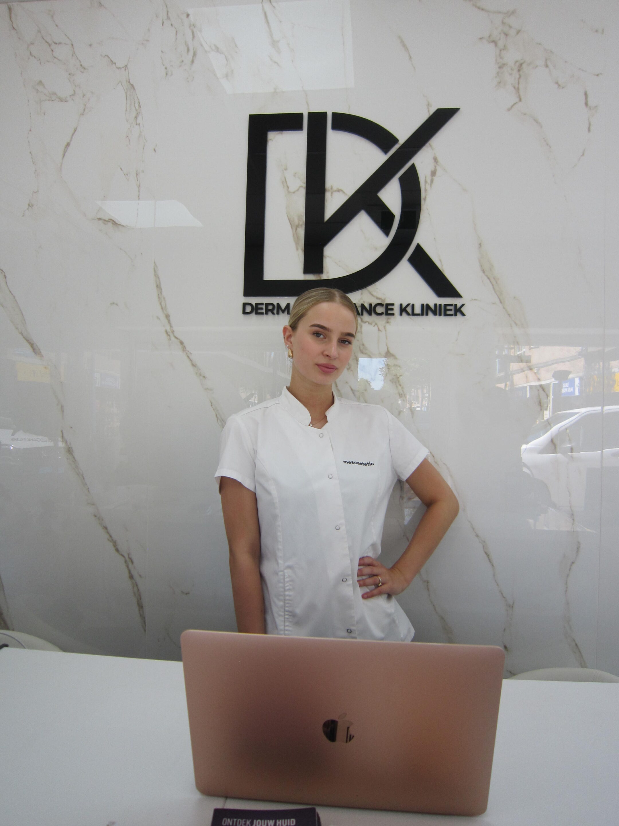 Een fles gezichtsreiniger, twee wattenschijfjes en een tube crème op een lichte achtergrond, symbool voor huidverzorgingsproducten.